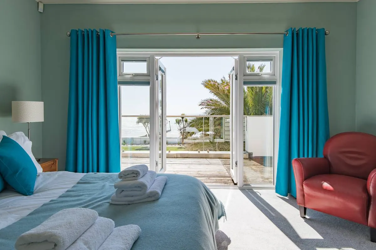 A bedroom with French doors open to the balcony and the sea