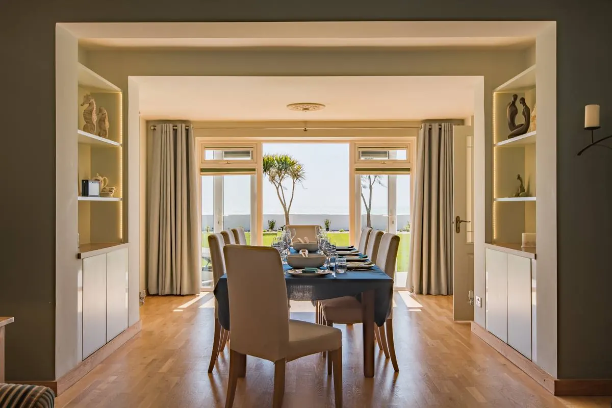 A dining table laid for dinner with the sea through the windows