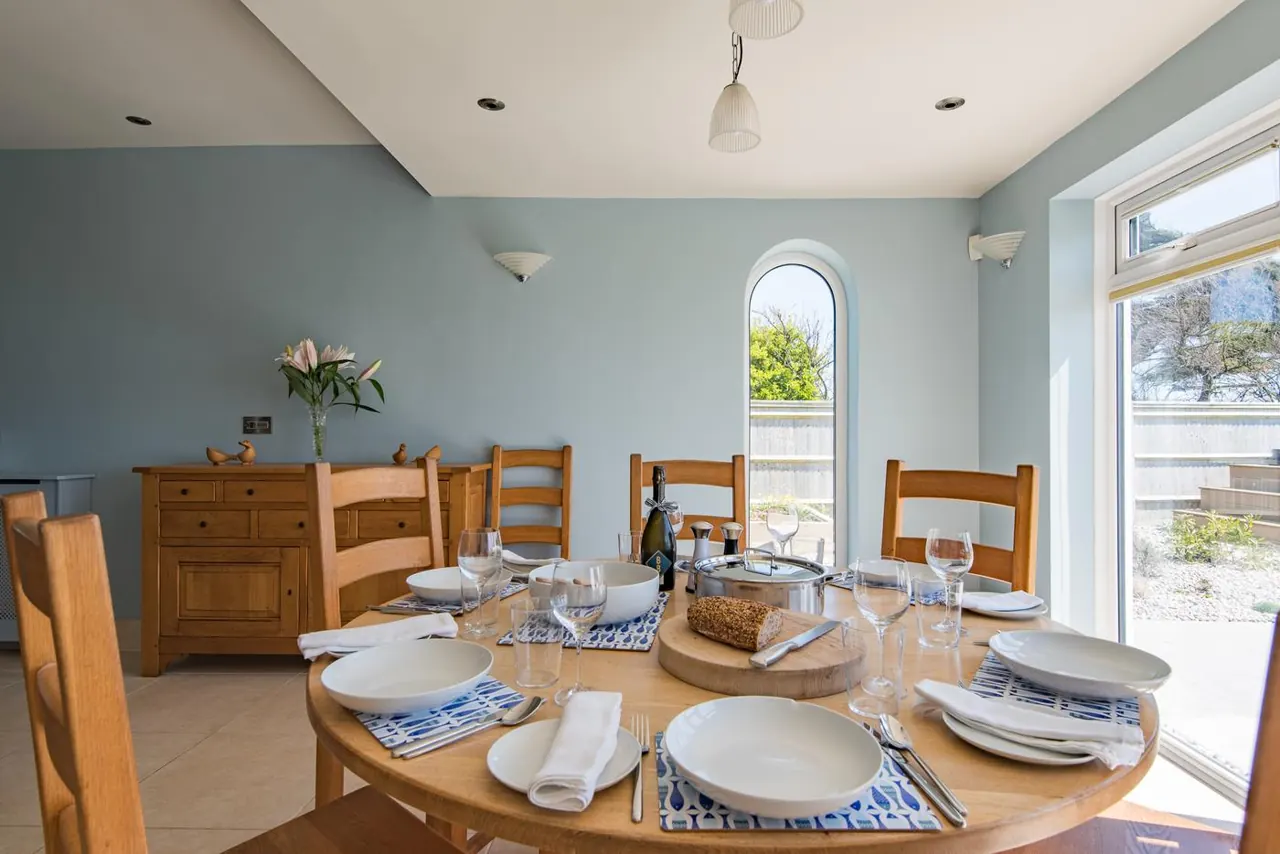 A round table laid for dinner beside the garden windows